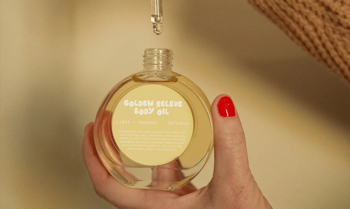 A hand holding a bottle of Golden Releve body oil